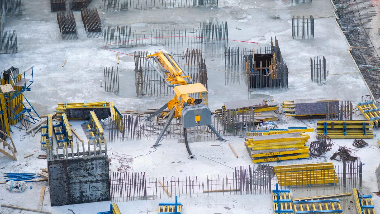 Chantier de construction en hiver : cages d’armatures de colonnes et coffrages sur une dalle enneigée